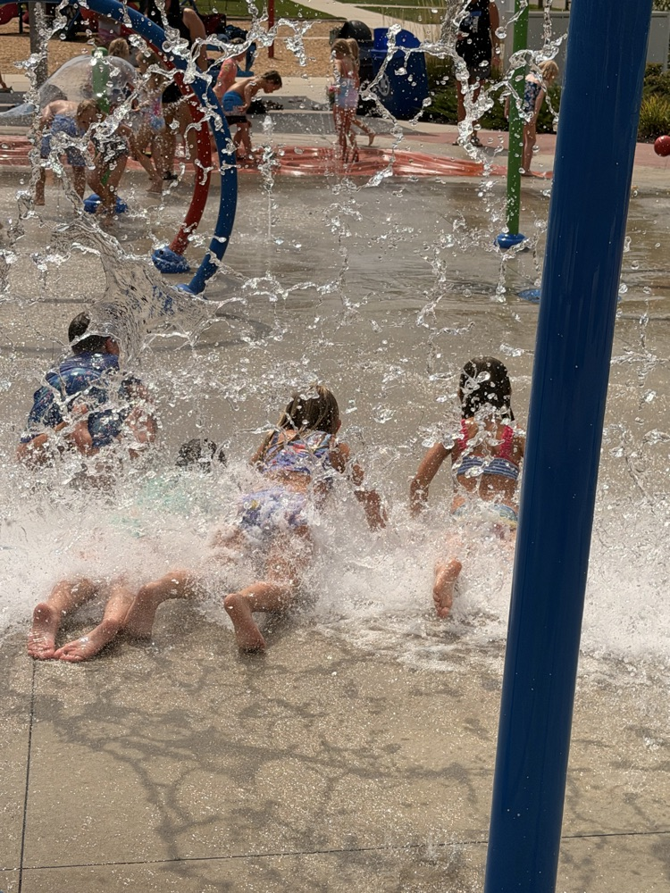 students playing in water at a splash pad