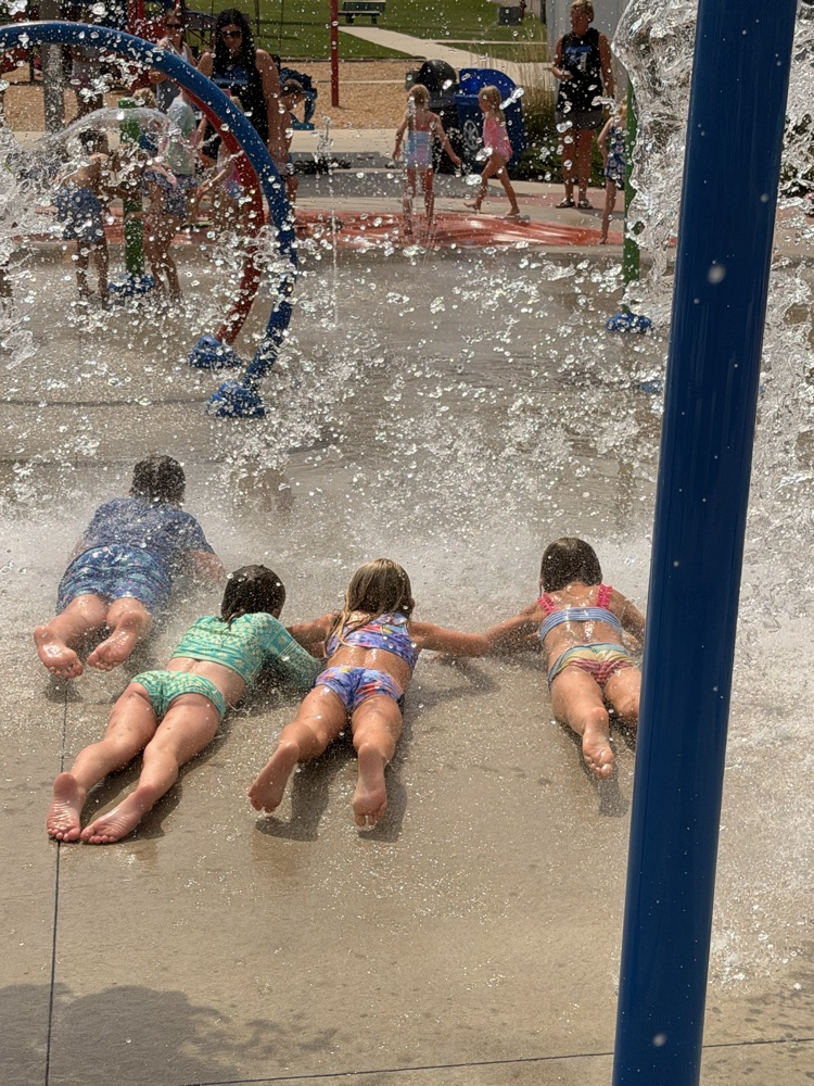 students playing in water at a splash pad