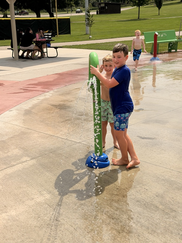 two students playing at a splash pad
