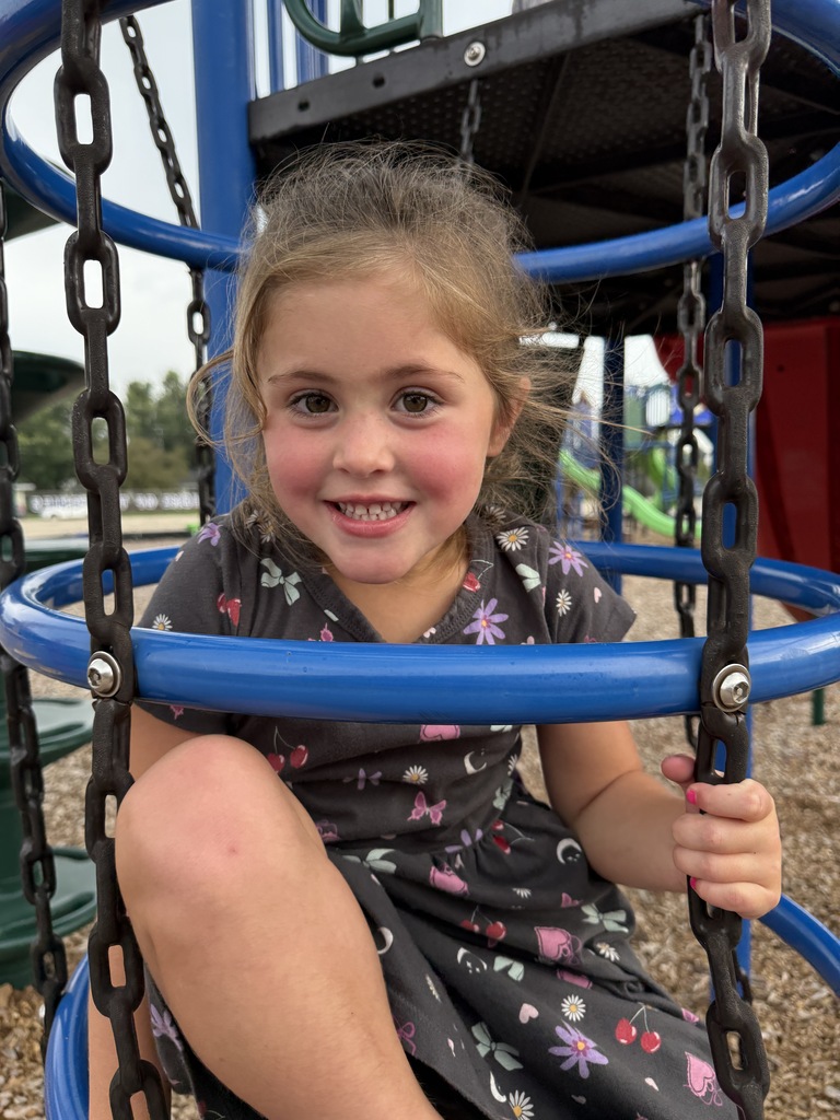 student smiling on playground equipment