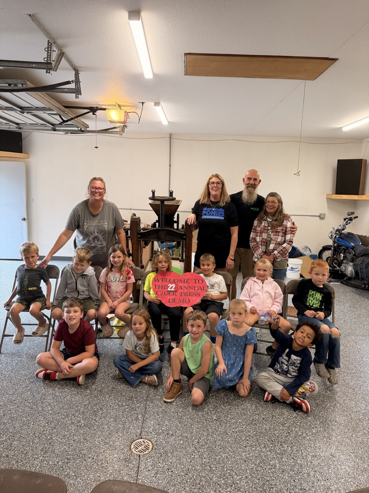 a group of students and adults with apple press
