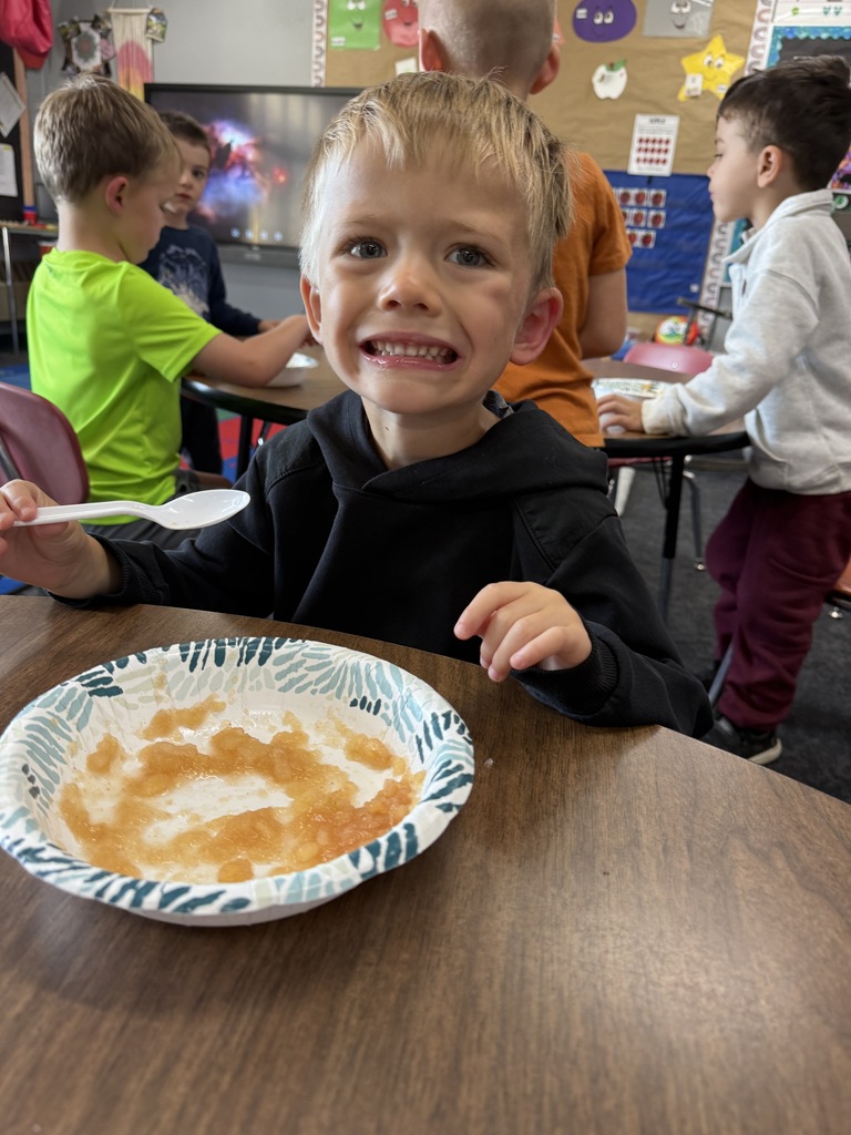 student smiling and eating apple sauce