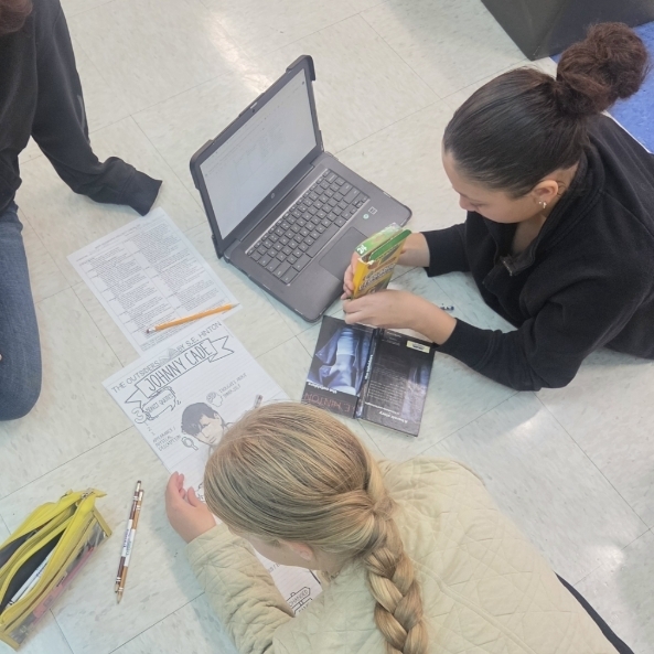 Girls working on a character poster for the book, The Outsiders.