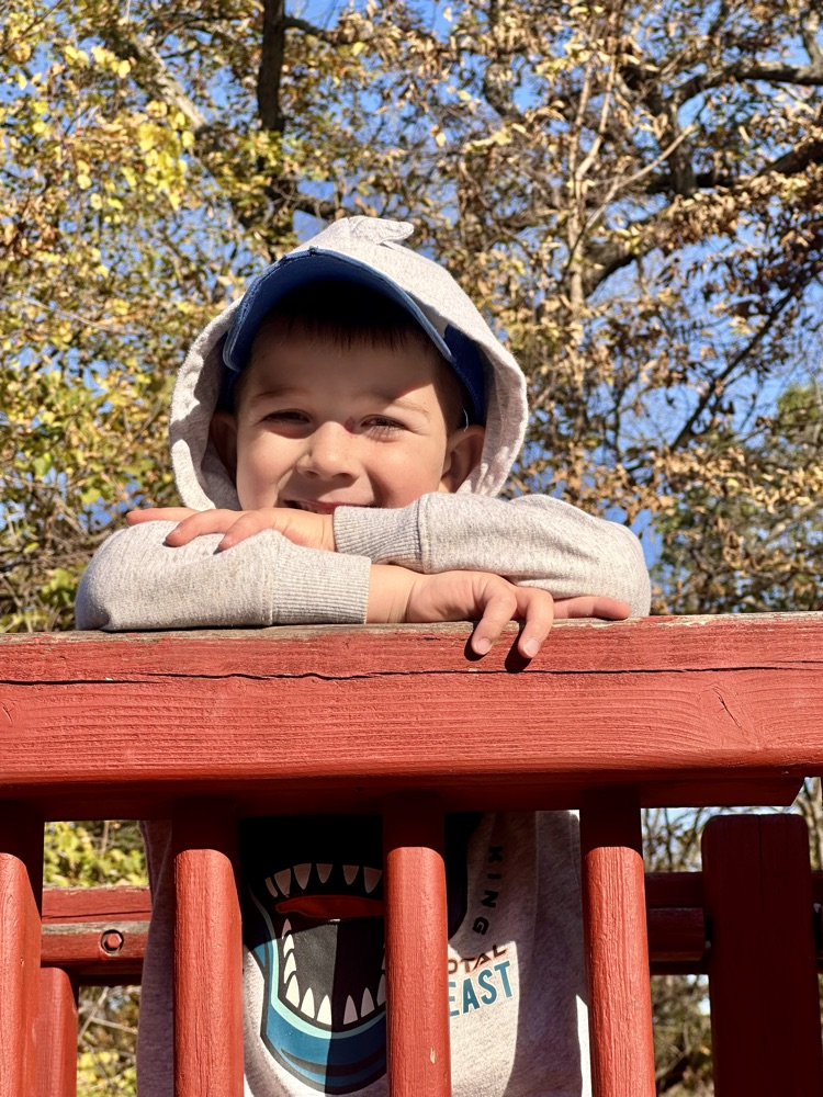 Student smiling on playground equipment.