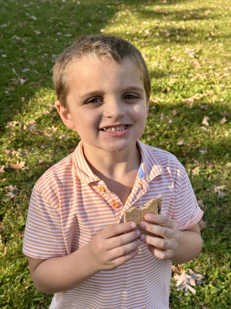 Student smiling and holding a s'more.