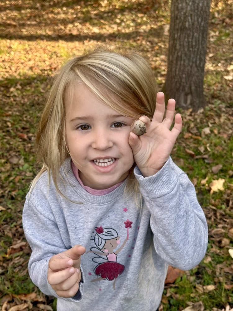 Student smiling and holding an acorn.