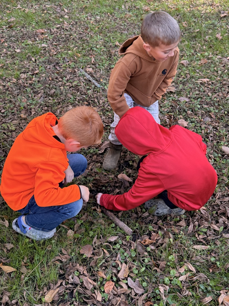 Three children playing with sticks.