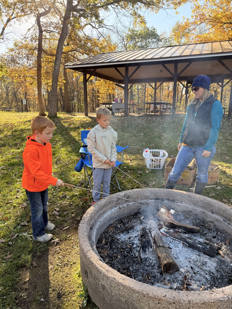 Two children and an adult roasting marshmallows.