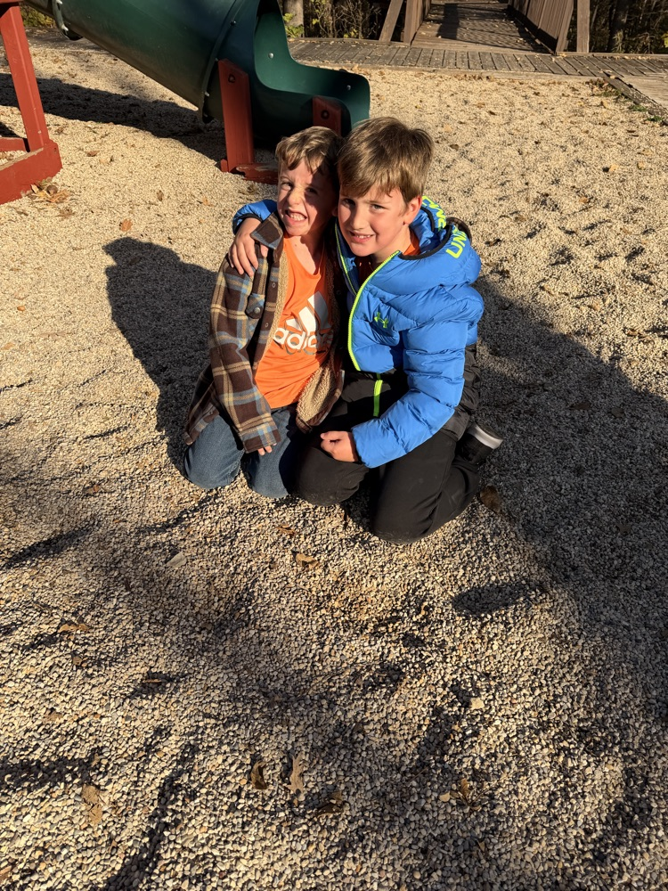 Two children kneeling on a playground.