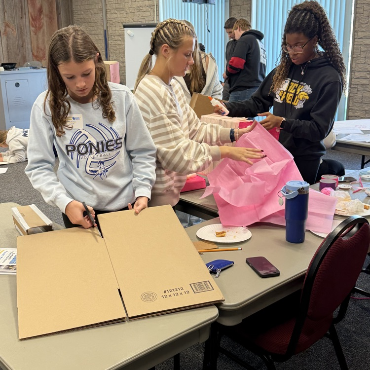 FBLA students creating a laundreybot with cardboard and tissue paper.