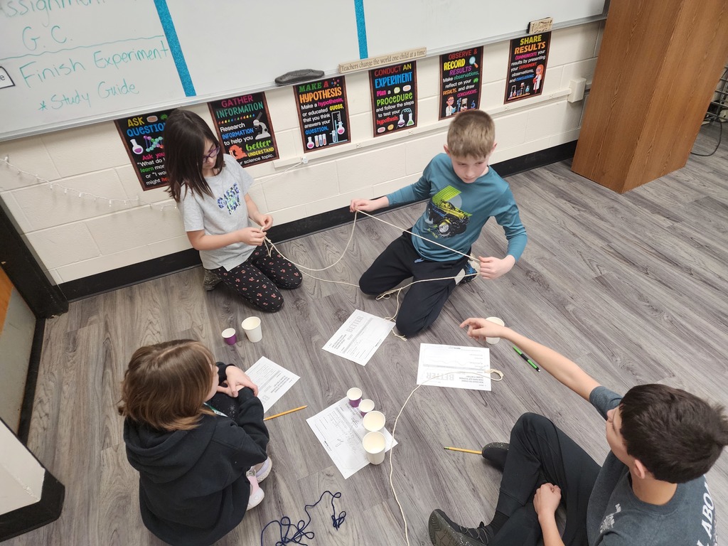 Students are making changes to their paper cup telephone to see if it will continue to work. 