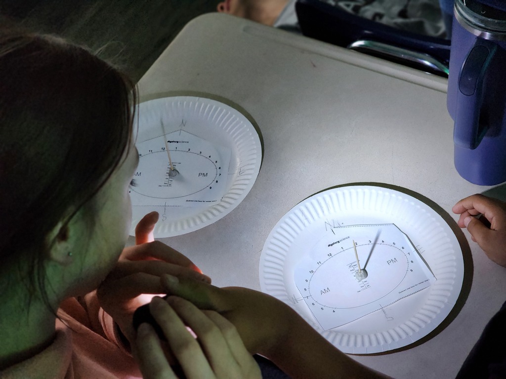 Students are exploring how the position of light affects the time shown on the clock.