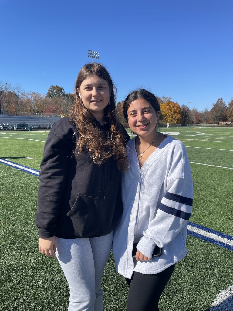 Two students pose outside on the football field