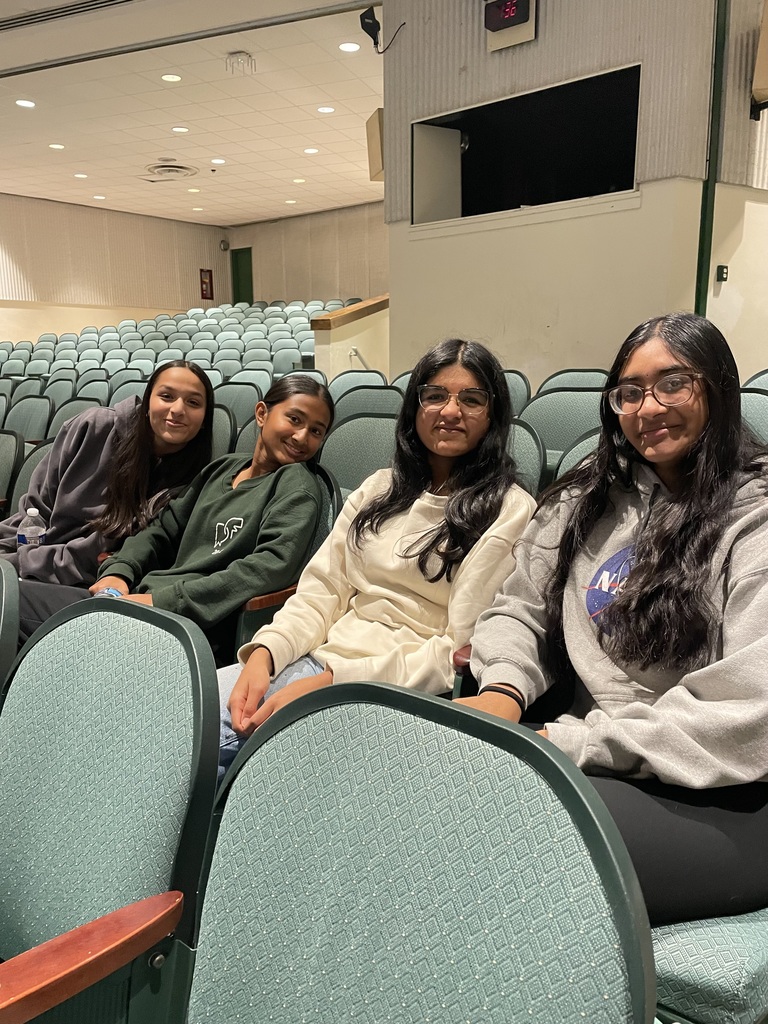 four students pose in the auditorium during the presentation