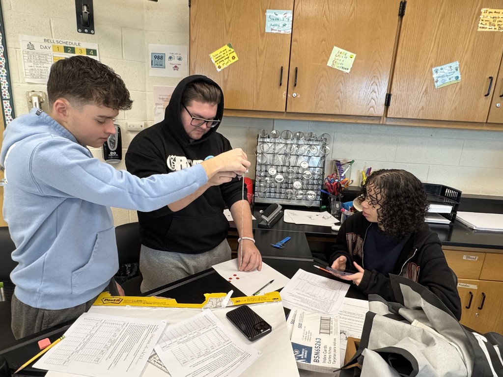 Three students participate in a blood spatter lab.