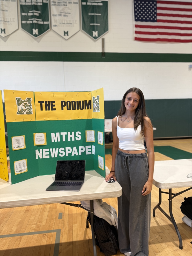 Student poses with the school newspaper - The Podium - trifold during the annual Club Fair