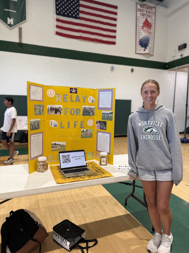 student poses with the Relay for Life Trifold during the club fair. 