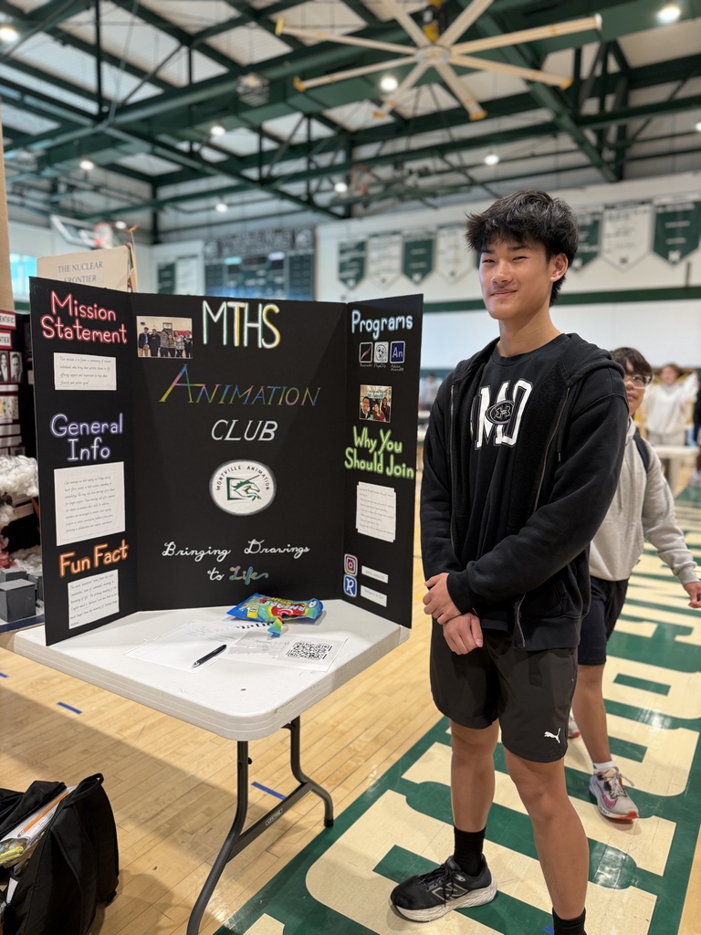 Student stands next to presentation trifold for the Animation Club during today's Club Fair