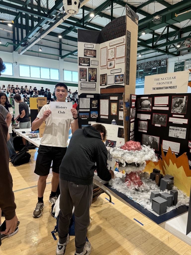 Student poses with a sign that says "History Club" during the Club Fair held during lunch today. 