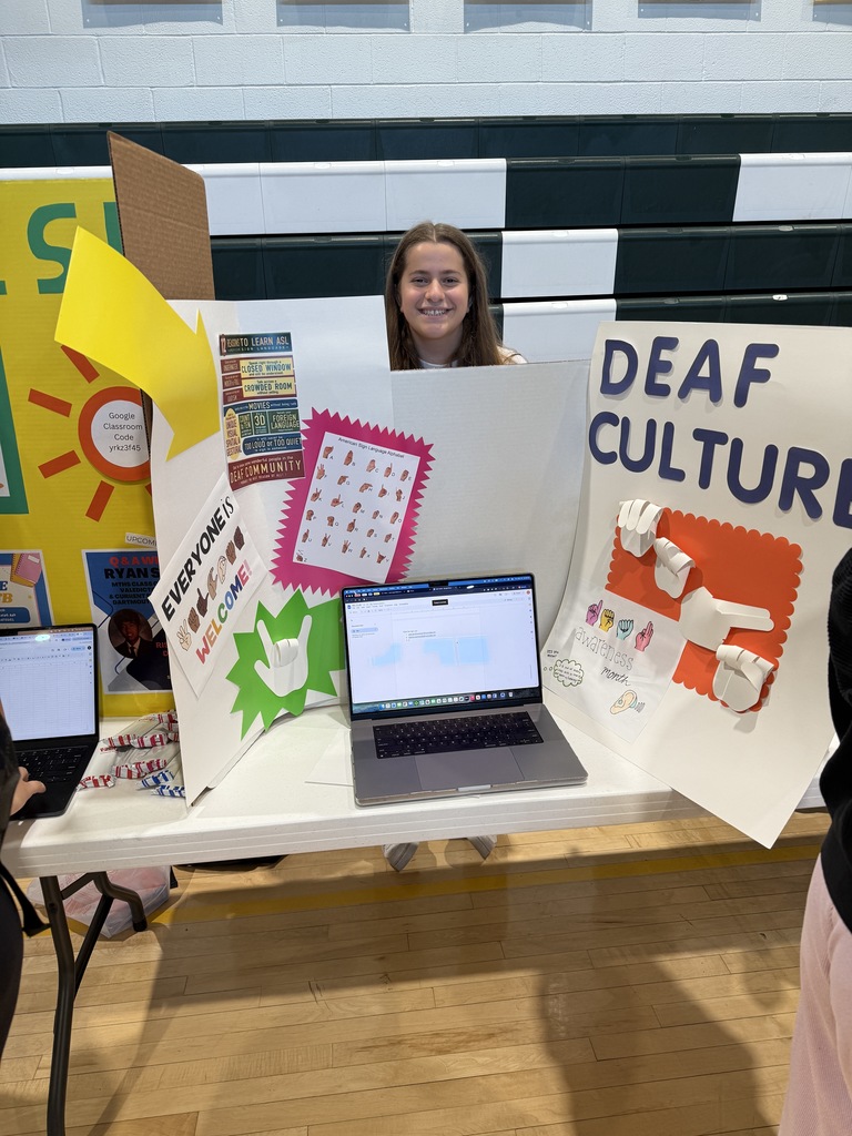 Student poses with the deaf culture trifold during the annual club fair 