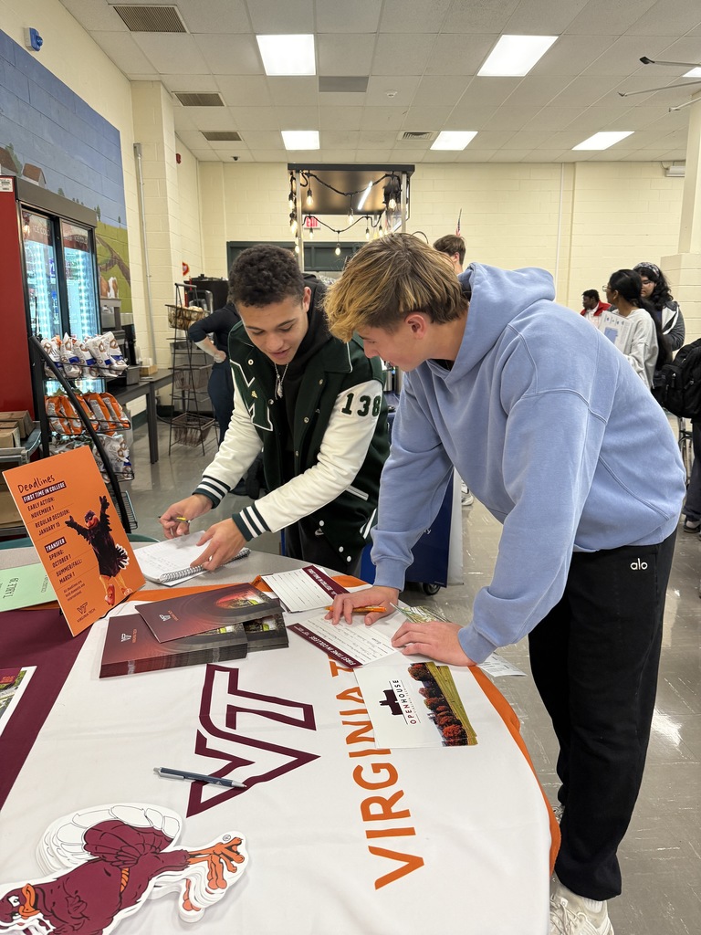 Two students fill out information cards at the  Virginia Tech table at the high school college fair