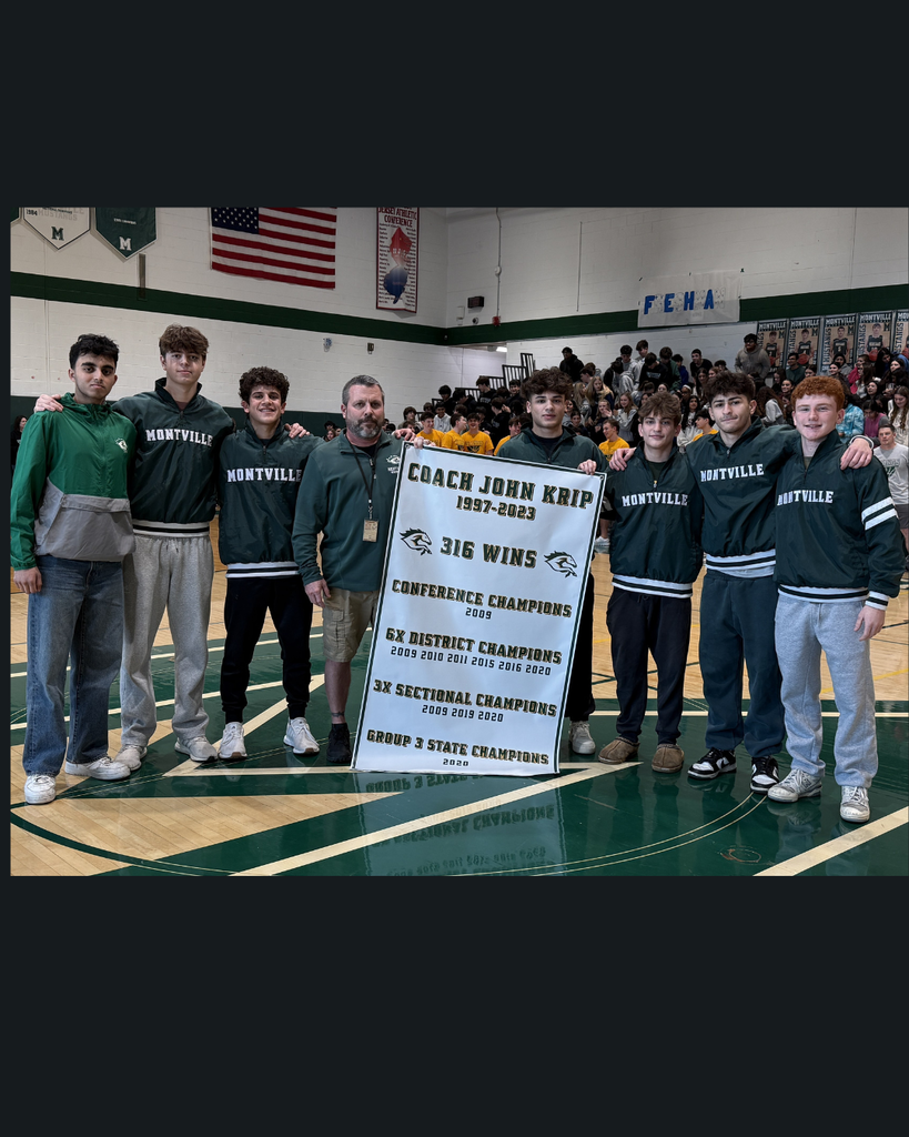 Picture of Coach John Krip with some members of the wrestling team standing with the new banner that will hang in the wrestling gym