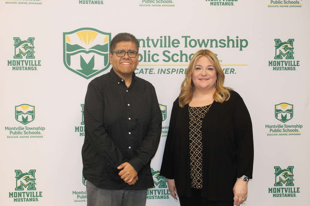Two people smiling in front of a "Montville Township Public Schools" backdrop. Both are wearing dark clothing, conveying a welcoming and professional tone.