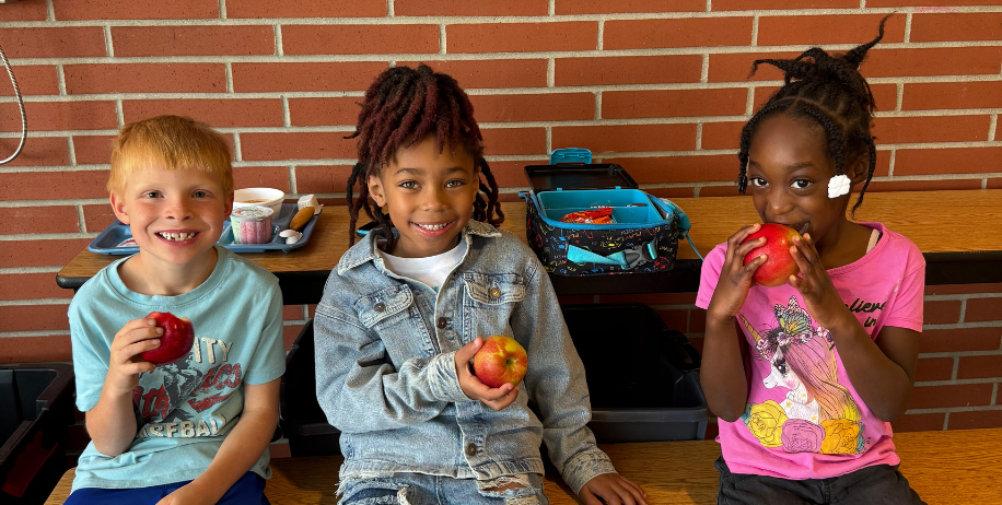 Three students eating apples at lunch