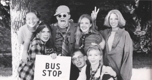 Todd Schultz, Lea Tkachuk, Erin Swetland, Racher Broten, Aarin Tomhave, Alissa Lyons and Katie Olson  waiting for the bus with a bus stop sign posing and having fun