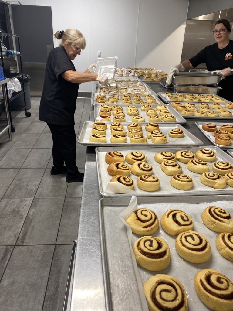 Adding frosting to freshly baked cinnamon rolls