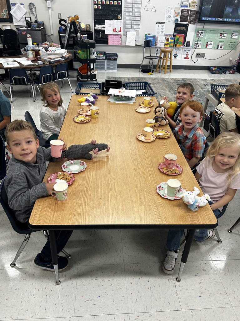 5 students smiling during the tea party at their table.