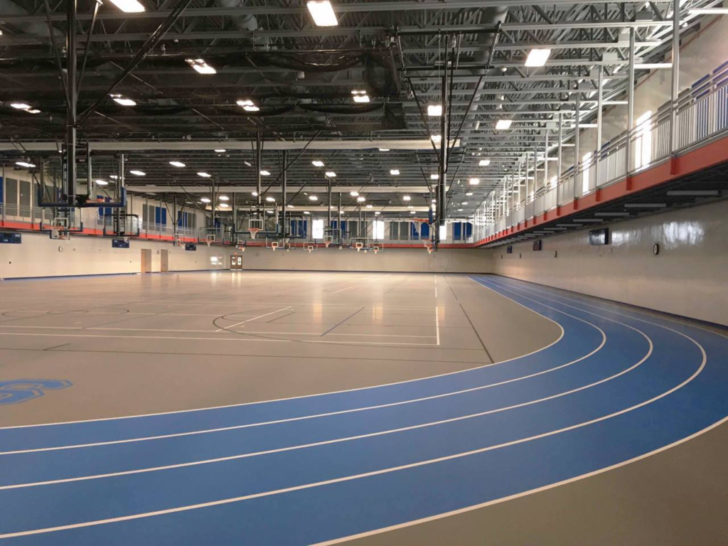 Photo of the Welia Center courts and track in Mora Public Schools. Basketball hoops and gray courts with blue track around the outside. 
