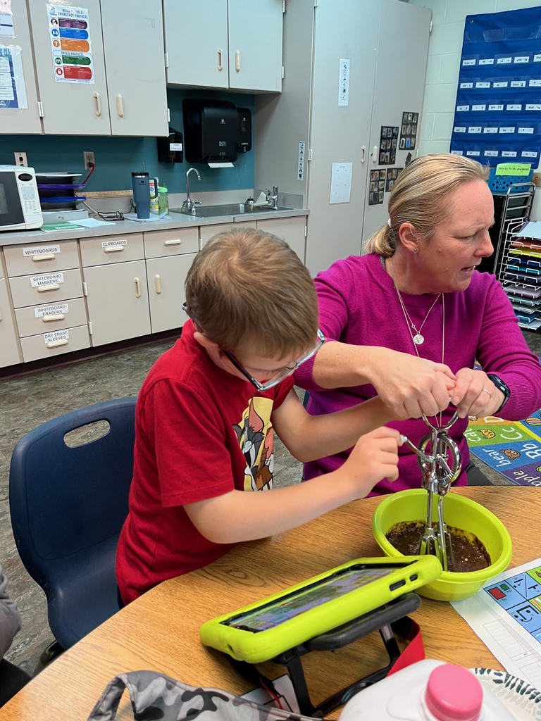 A student and staff member making chocolate pudding.