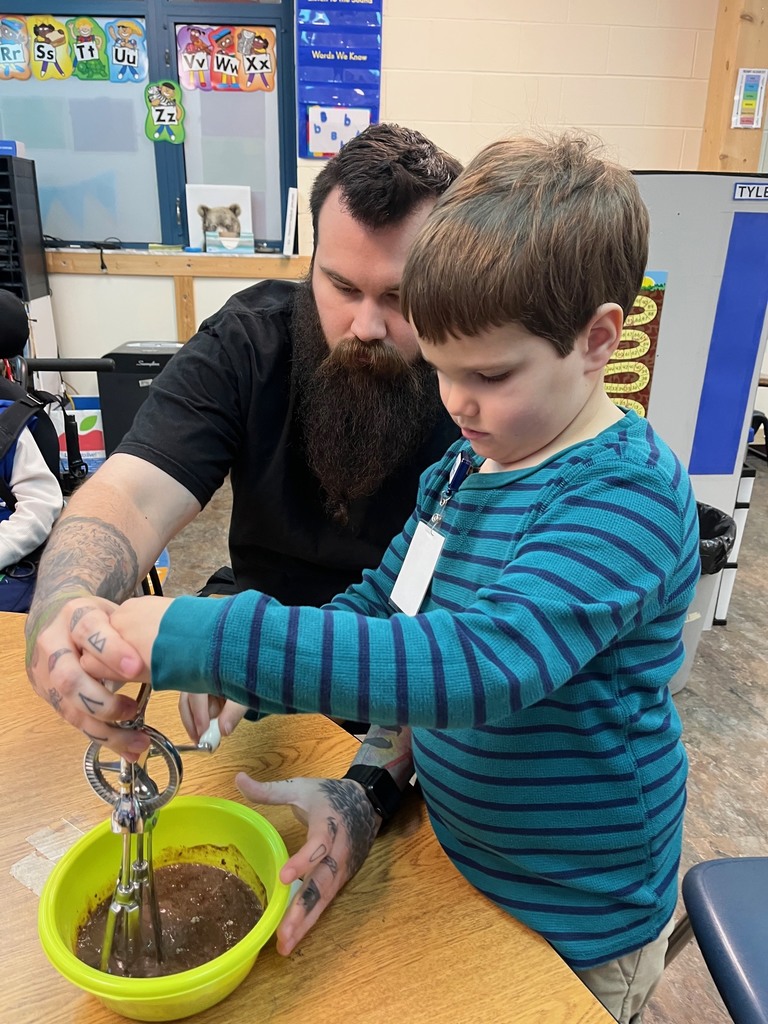 A staff member showing a student how to mix chocolate pudding.