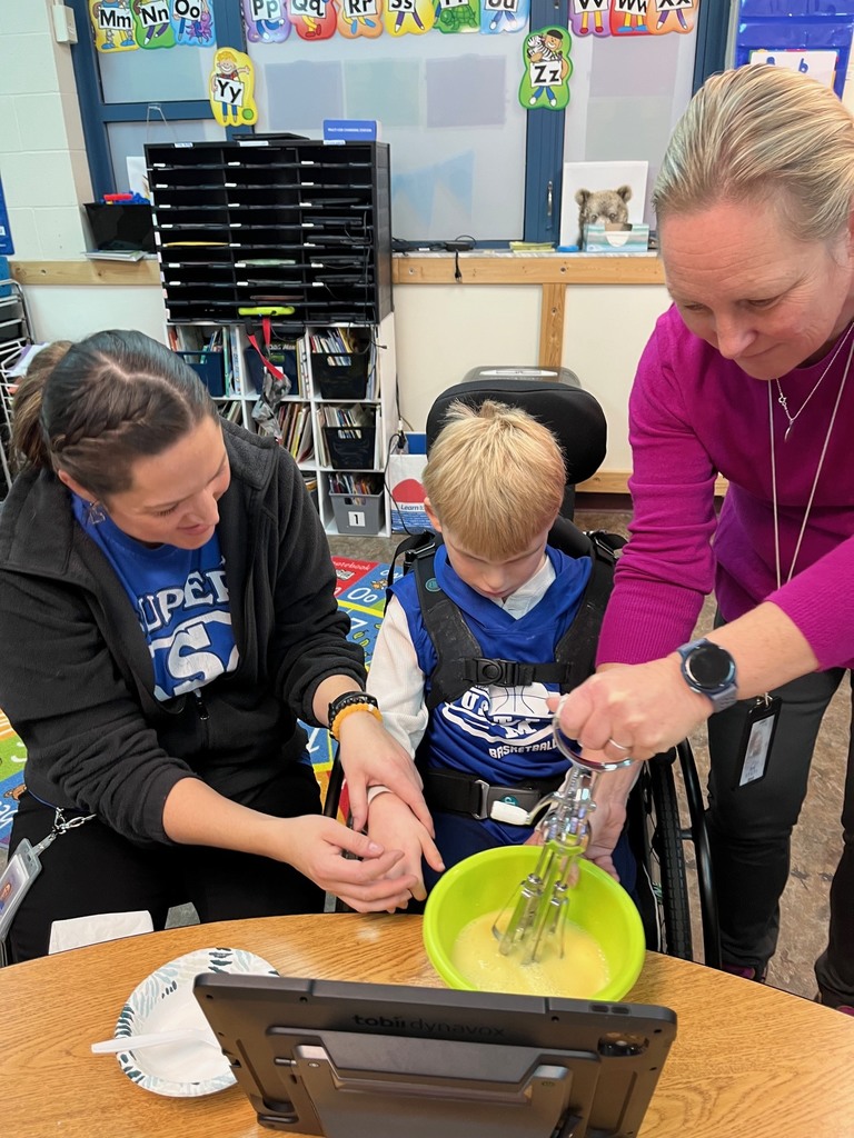 Two staff helping a student making vanilla pudding.