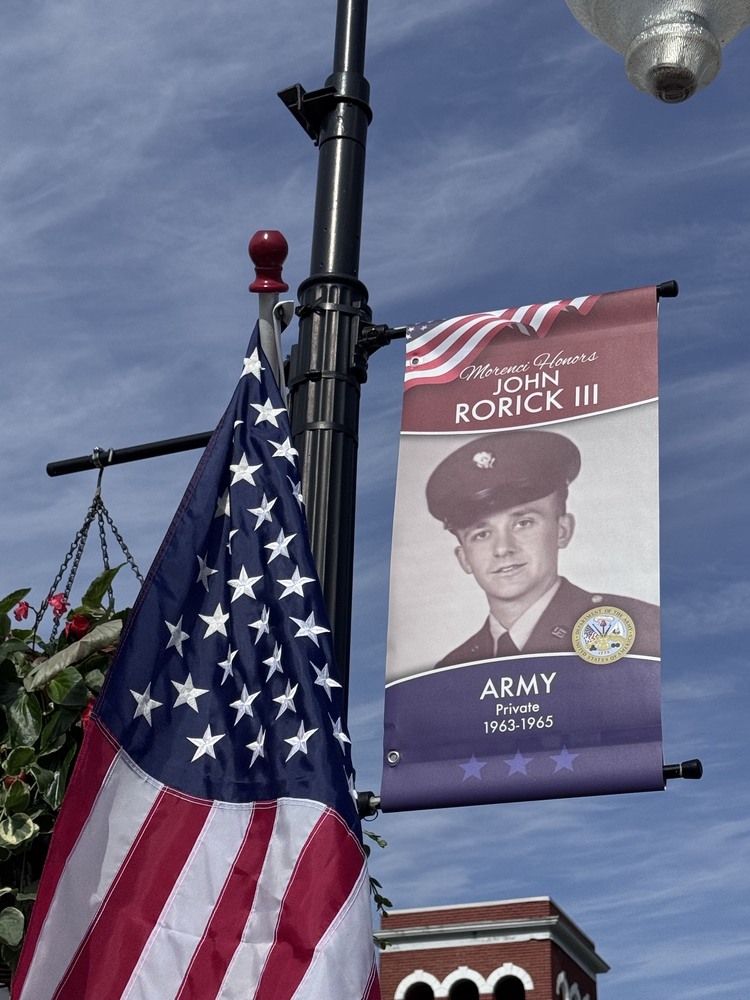 Banner of John Rorick 3 Army hung on light pole in downtown morenci with flag