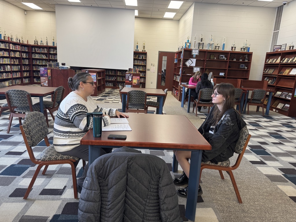 student being interview by an adult in the library