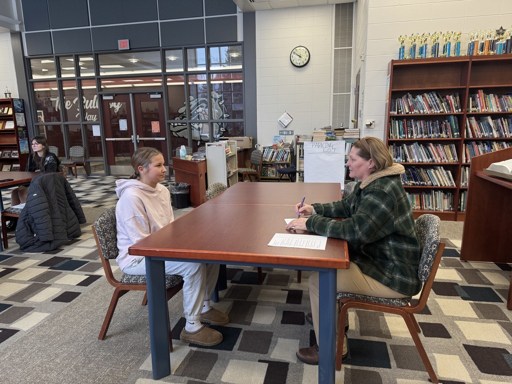 student being interview by an adult in the library
