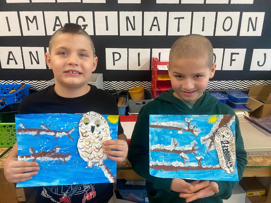 students holding their painted owl project