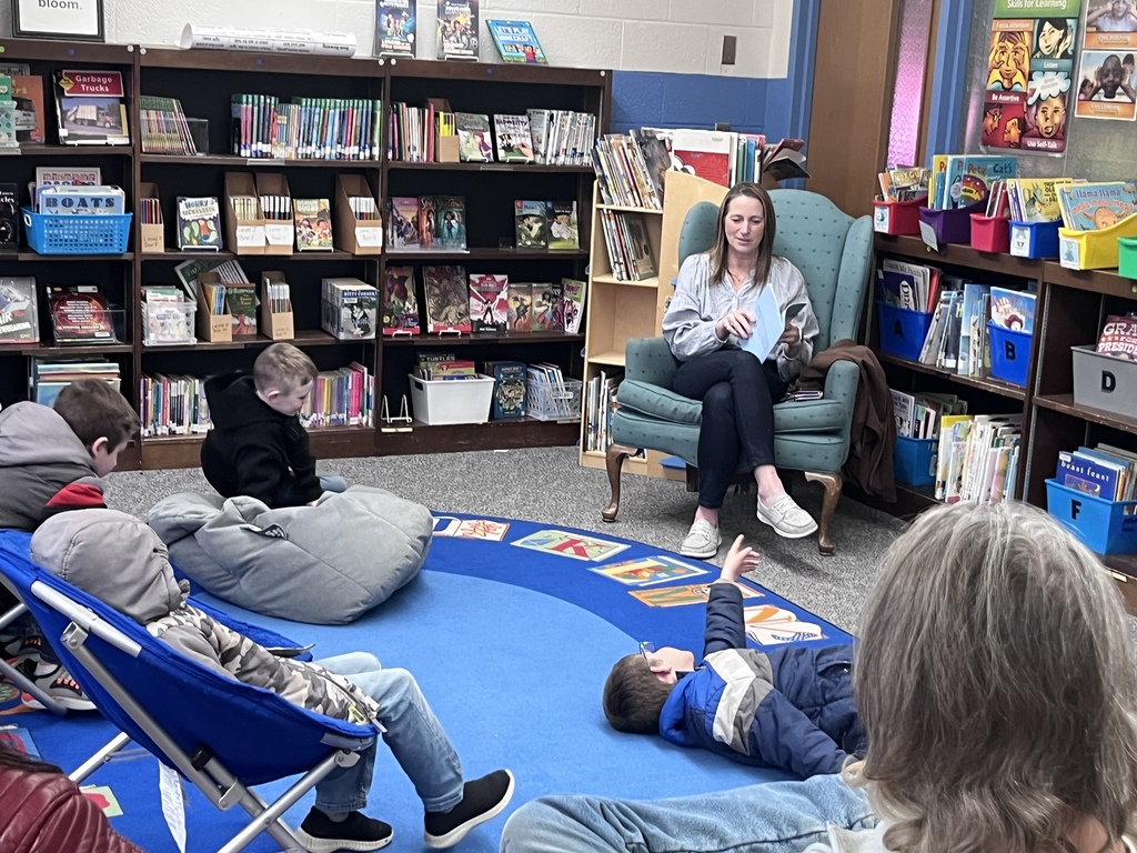 teacher reading a book to a group of students