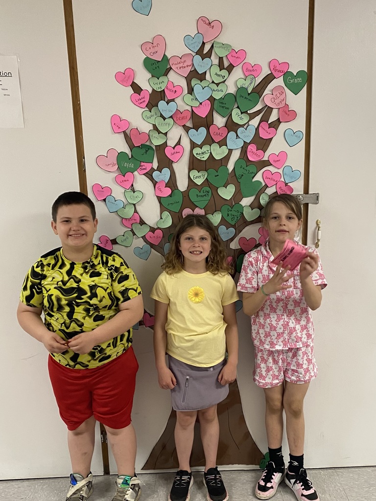 three students standing in front of the kindness tree