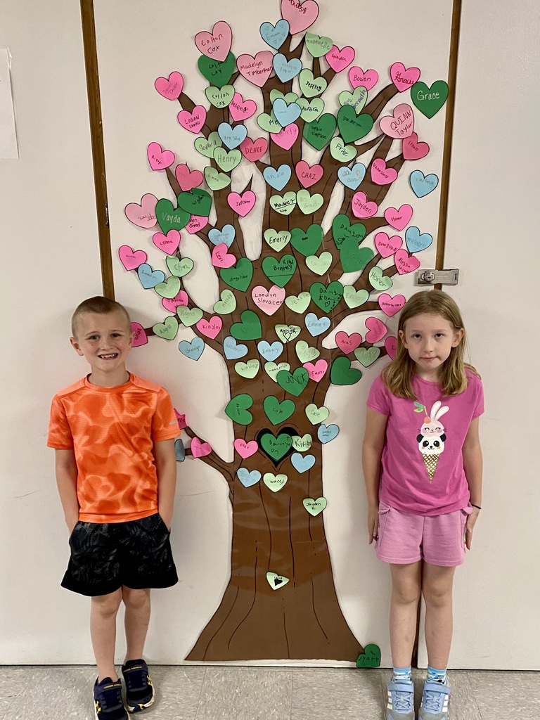 two students standing in front of the kindness tree