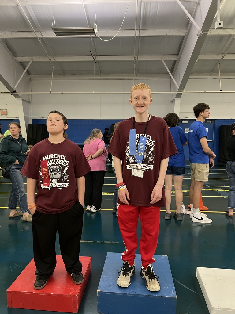 two students standing on a podium with ribbons around their necks that they won at the special olympics.