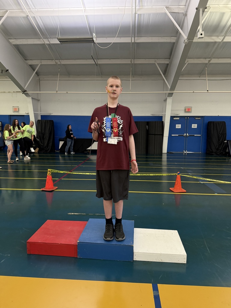 student standing on podium with his ribbons he won.