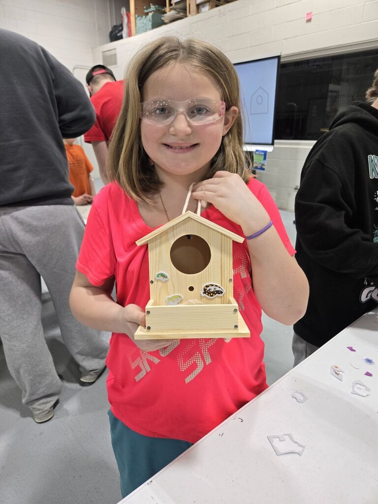 student showing off his birdhouse she made.