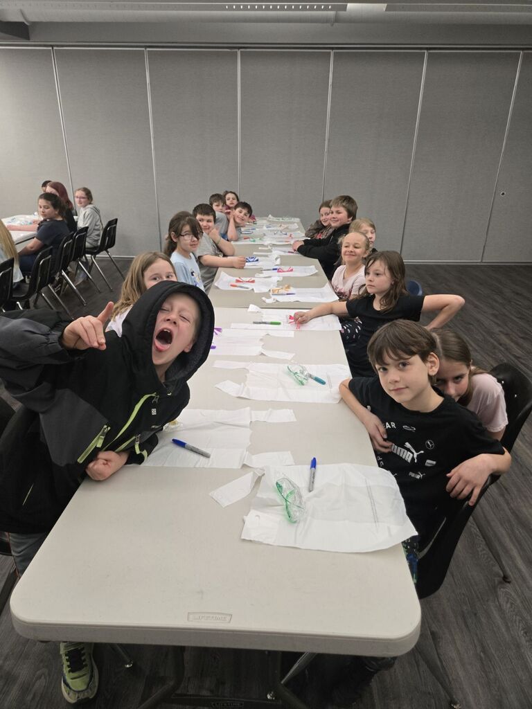 students sitting at a table learning a lesson.