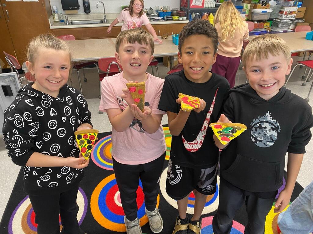 group of students showing off their final piece of pizza all painted.