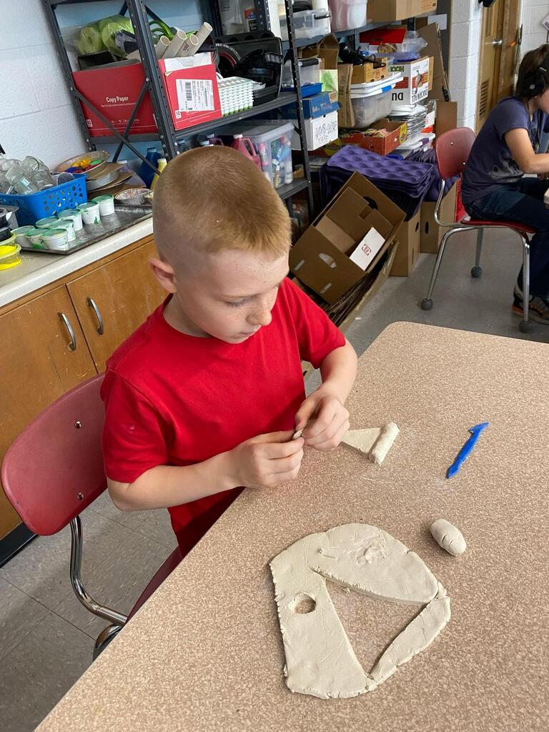 student creating ceramic slice of pizza and coloring it.