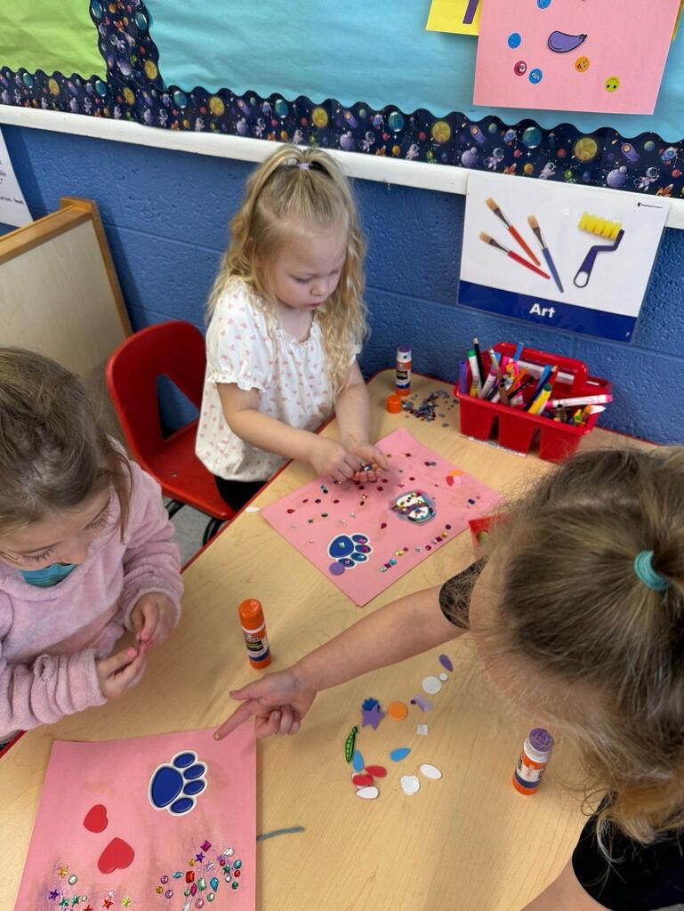 three students doing a craft with glue