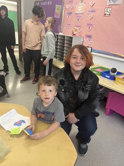 Kindergarten and 8th grade student posing for picture with the stuffed animal that was made for them.